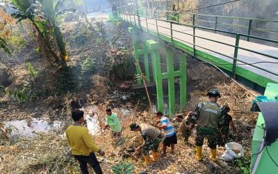  Personel Satgas TMMD ke-129 Kodim 0813/Bojonegoro bersama warga melaksanakan kerja bakti membersihkan area Jembatan Brang Etan, Desa Kesongo, Kecamatan Kedungadem, Kabupaten Bojonegoro.