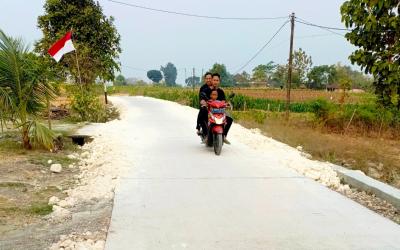 Warga melintas di jalan cor beton hasil pembangunan TMMD ke-129 sepanjang 550 meter di Dusun Kedungpandan, Desa Kesongo, Kecamatan Kedungadem, Kabupaten Bojonegoro, Senin (10/8/2026). Foto: Deni Flamboyan/Sumber TMMD Bojonegoro