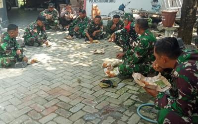 Usai mengerjakan berbagai sasaran fisik, personel Satgas TMMD ke-129 Kodim 0813/Bojonegoro beristirahat sejenak dengan menikmati makan siang menggunakan nasi bungkus sambil duduk lesehan di lokasi pekerjaan, Rabu (22/7/2026).