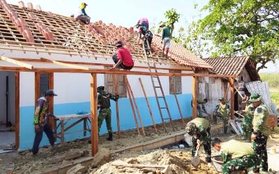 Babinsa Desa Kesongo Serka Lasmidi bersama anggota Satgas TMMD ke-129 Kodim 0813 Bojonegoro dan warga bergotong royong memasang genting pada rumah penerima program RTLH di Desa Kesongo, Kecamatan Kedungadem, Kabupaten Bojonegoro, Minggu (09/08/2026). Foto: Deni Aripandi/Sumber TMMD Bojonegoro.