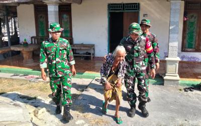 Babinsa Desa Kesongo Serka Lasmidi mendampingi Mbah Kasidah melihat proses rehabilitasi rumah putranya, Bapak Ladi, dalam program TMMD ke-129 Kodim 0813 Bojonegoro di Desa Kesongo, Kecamatan Kedungadem, Jumat (7/8/2026).