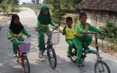 Dengan sepeda yang mereka kayuh penuh semangat, perjalanan menuju sekolah kini terasa lebih nyaman setelah akses jalan di wilayah mereka berubah menjadi lebih baik.