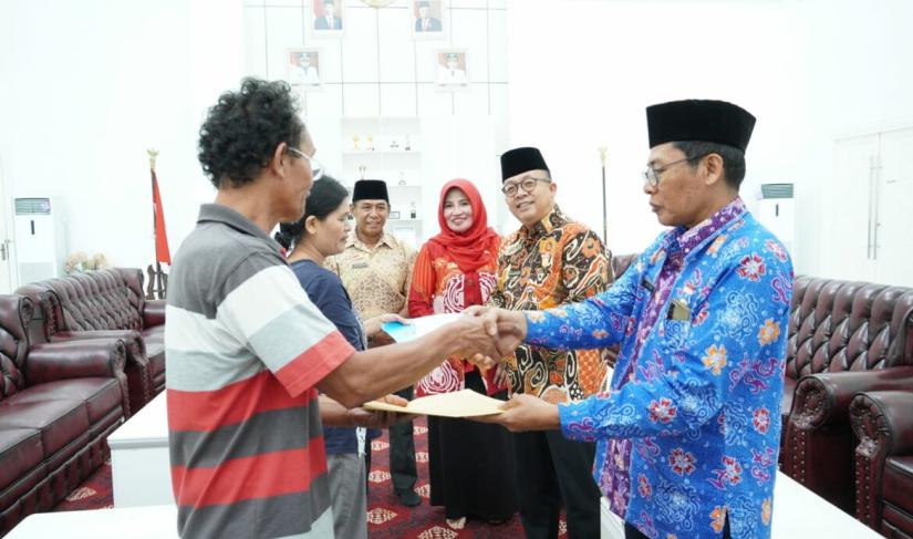 Asisten I Eko Agusrianto menyerahkan bantuan untuk pemindahan makam di Kelurahan Pekan Sabtu kepada 2 orang ahli waris makam, Kamis (11/5/23)