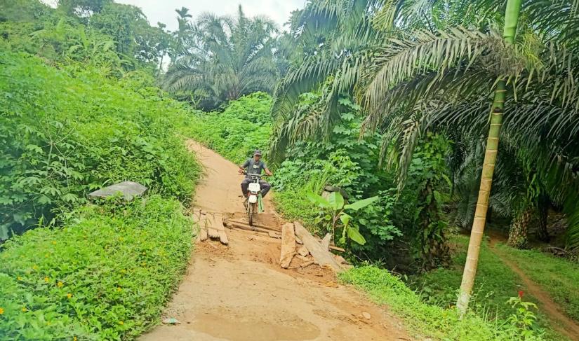 JEMBATAN RUSAK  : Salah satu warga melewati jembatan penghubung antara Desa Sinar Mulya dan Desa Arga Mulya terlihat rusak parah dan tidak terawat, Minggu (03/03).