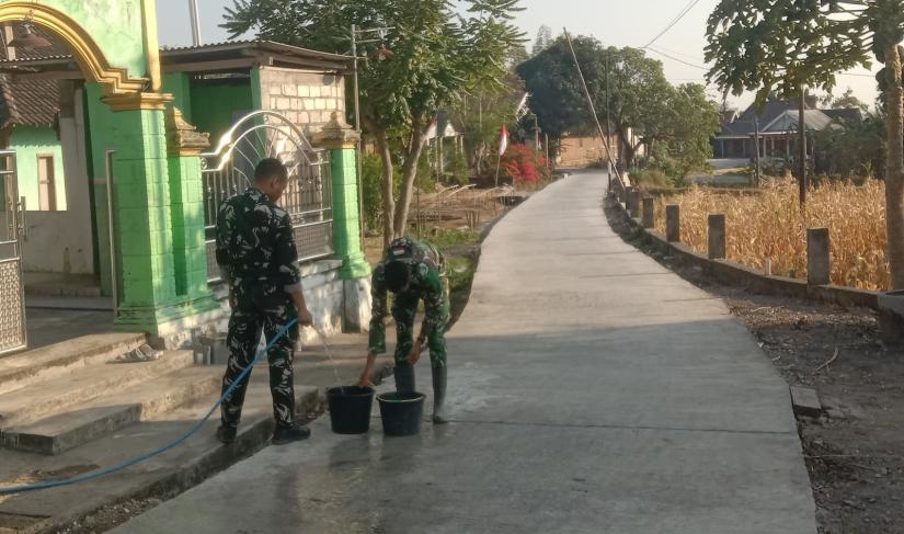Personel Satgas TNI Manunggal Membangun Desa (TMMD) ke-129 Kodim 0813/Bojonegoro bersama warga melaksanakan perawatan jalan beton yang telah selesai dicor di Dusun Kedungpandan, Desa Kesongo, Kecamatan Kedungadem, Kabupaten Bojonegoro, Minggu (2/8/2026).