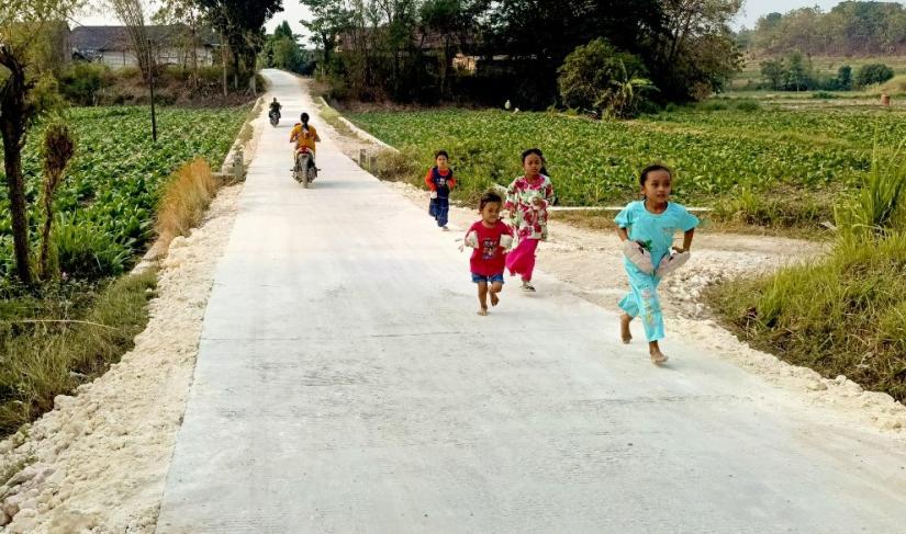  Anggi bersama teman-temannya bermain dan berlari di jalan cor hasil pembangunan TMMD ke-129 Kodim 0813 Bojonegoro di Dusun Mundu, Desa Kesongo, Kecamatan Kedungadem, Kabupaten Bojonegoro, Minggu (09/08/2026). Foto: Deni Ari Pandi/Sumber: TMMD Bojonegoro.