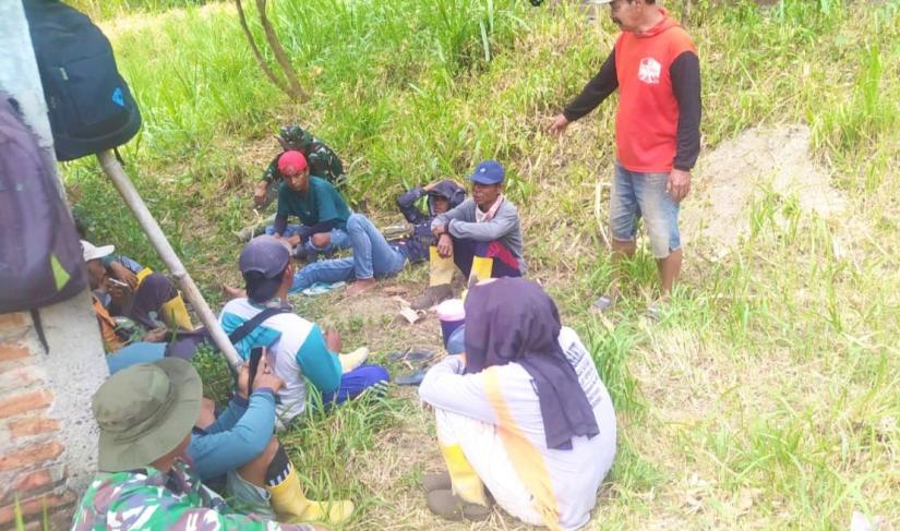 Suasana hangat tampak saat sejumlah prajurit TNI bersama warga memanfaatkan waktu istirahat dengan duduk lesehan di bawah rindangnya pepohonan di tepi jalan. Sambil menunggu kedatangan truk pengangkut material cor beton, mereka menikmati secangkir kopi dan berbincang santai tanpa sekat.