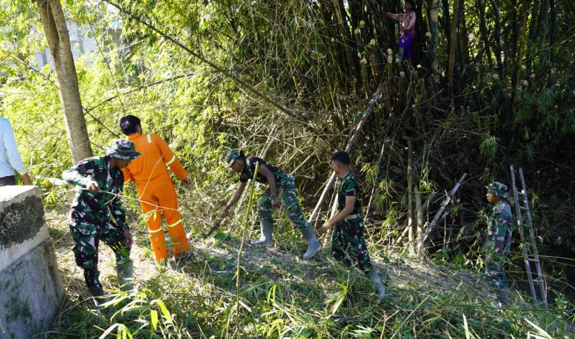 Melalui aksi gotong royong, personel Satgas TMMD bersama masyarakat melaksanakan kerja bakti membersihkan bantaran Sungai Kesongo di sekitar Jembatan Brang Etan, Desa Kesongo, Kecamatan Kedungadem, Minggu (26/7/2026).