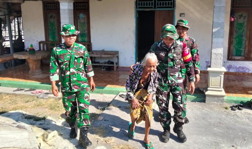 Babinsa Desa Kesongo Serka Lasmidi mendampingi Mbah Kasidah melihat proses rehabilitasi rumah putranya, Bapak Ladi, dalam program TMMD ke-129 Kodim 0813 Bojonegoro di Desa Kesongo, Kecamatan Kedungadem, Jumat (7/8/2026).