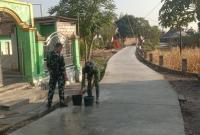 Personel Satgas TNI Manunggal Membangun Desa (TMMD) ke-129 Kodim 0813/Bojonegoro bersama warga melaksanakan perawatan jalan beton yang telah selesai dicor di Dusun Kedungpandan, Desa Kesongo, Kecamatan Kedungadem, Kabupaten Bojonegoro, Minggu (2/8/2026).